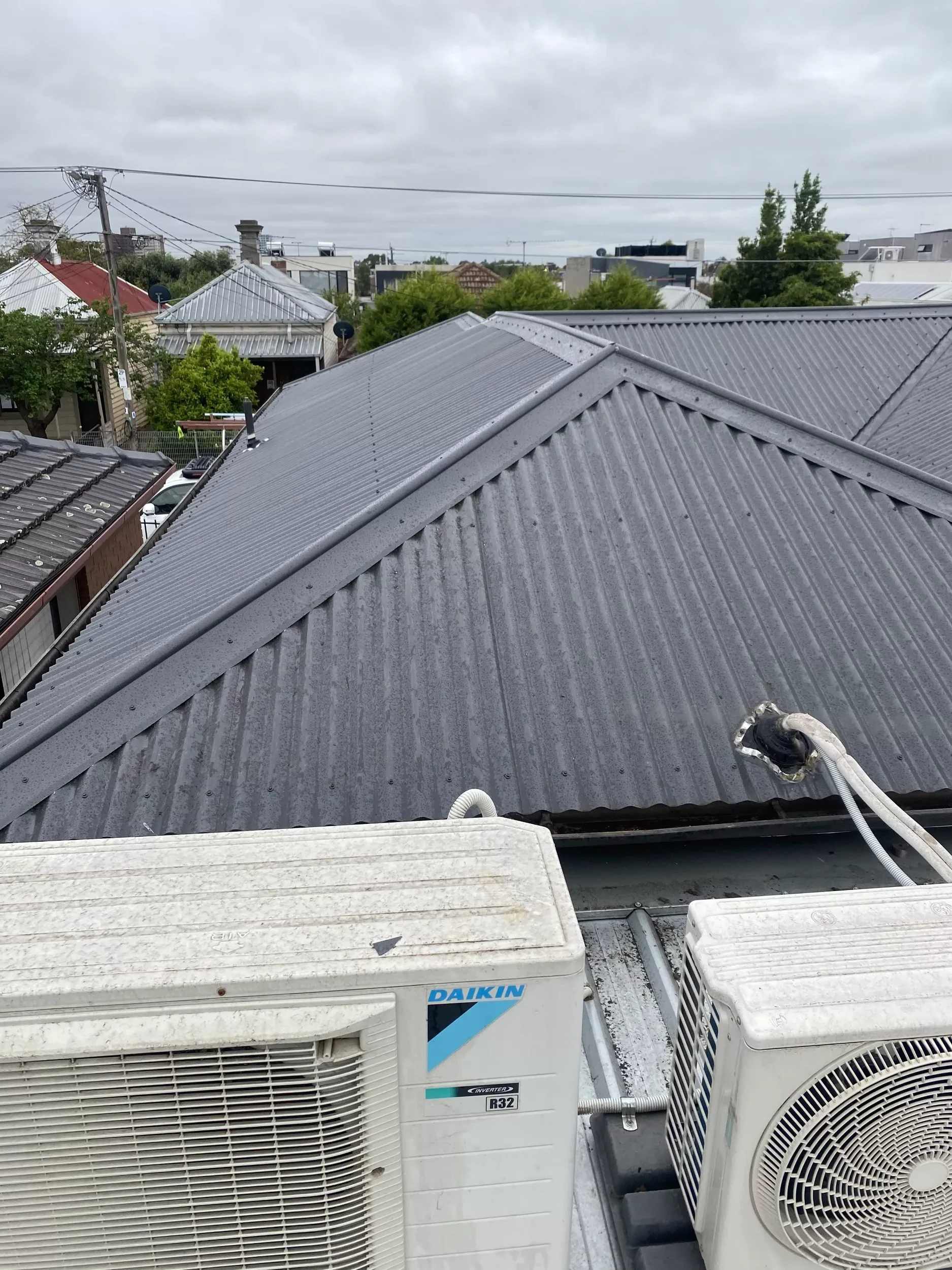 Close-up image of a gray galvanized roof next to an outdoor AC unit